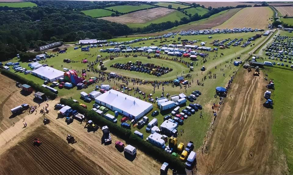 Thousands of people and classic vehicles can be seen from above at the Great Trethew Vintage Rally 2023 near Liskeard in Cornwall., There is a show ring in the centre and the visitors and vehicles span out across a number of farmer's fields